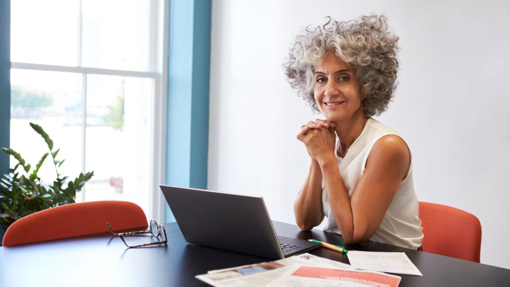 Woman working at a laptop thoughtfully.